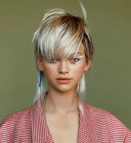 Fotografie v galerii od Jan Balcařík, který vytvořil vzhled této ženy. Zelené pozadí, žena odbarvený blond krátké vlasy. Fotka je z čelního pohledu. Na sobě má kostkované červeno bílé tričko.