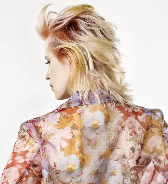 Nikol Hlaváčková je tvůrkyní tohoto účesu. Žena má délku vlasů po ramena a je blonďaté s odstínem červené u hlavy.